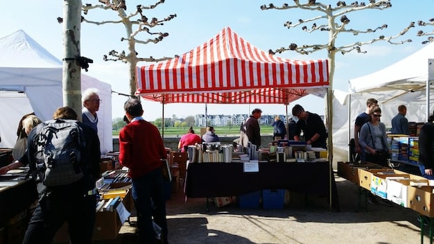 A bustling scene outside a music festival, showing food vendors, merchandise stands, and local businesses benefiting from the influx of festival attendees. The image should highlight the economic activity generated by the festival.