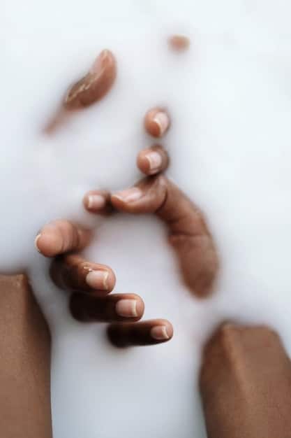 A close-up image of hands of various skin tones reaching towards a central pile of coins. The coins are diverse in denomination and origin, symbolizing collaborative wealth building across different backgrounds. Soft, diffused lighting highlights the unity and shared purpose.