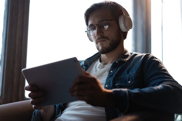 A music supervisor sitting in a brightly lit office, reviewing submissions on a tablet while wearing headphones. Various film posters are visible on the walls.