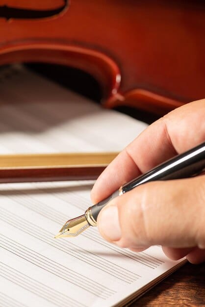A close-up of a hand signing a music licensing agreement, with a pen hovering over the signature line. Legal documents and a blurred office background suggest a professional setting.