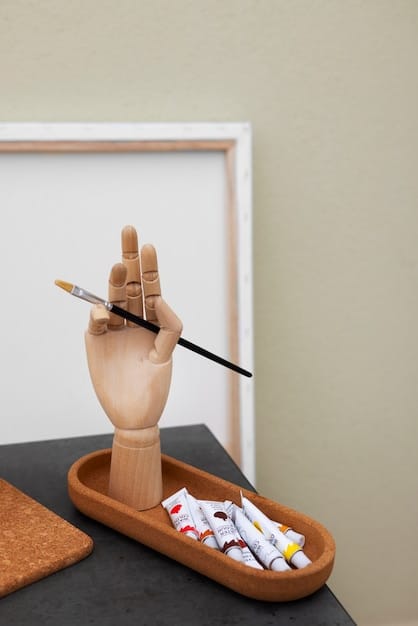 A close-up of an artist's hands working on a sculpture in a studio. The background includes various tools and art supplies, emphasizing the creative process.