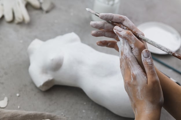 A close-up of an artist's hands meticulously crafting a sculpture in their studio, showcasing the dedication and skill involved in creating art.